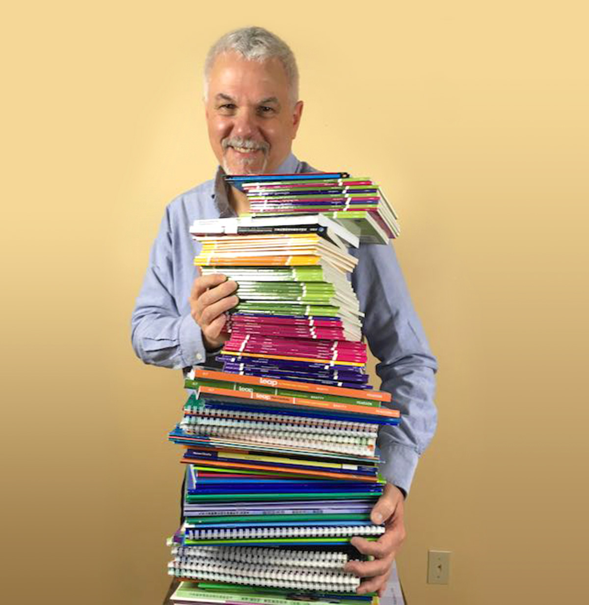 Dr. Ken Beatty holding a big stack of books