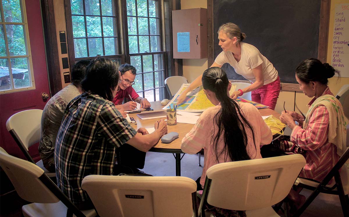 A teacher showing a map to a group of five English language students who are sitting around a table